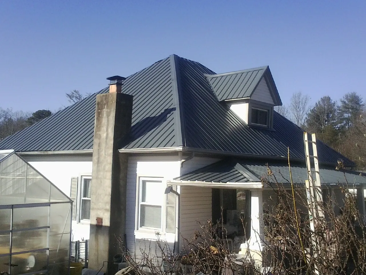 Dark blue standing seam metal roof on a white farmhouse with dormer — Slate & Tile Roof Repair by Roofing Brothers in Licking