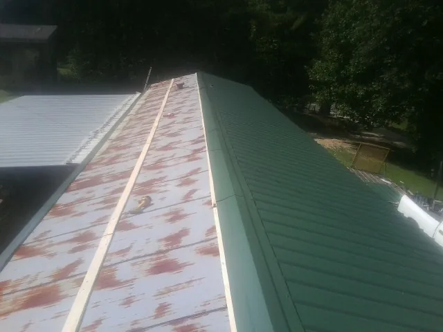 Old rusted panels beside newly installed green metal roofing — Wind Damage Roof Repair by Roofing Brothers in Licking