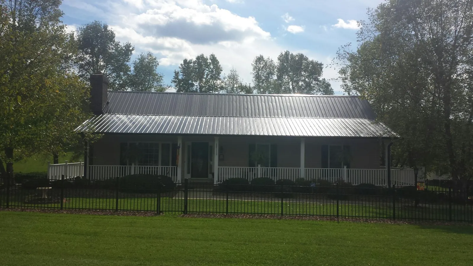 Gray metal roof on a brick ranch with a full width front porch — Gutter Guard Installation work by our crew in Licking