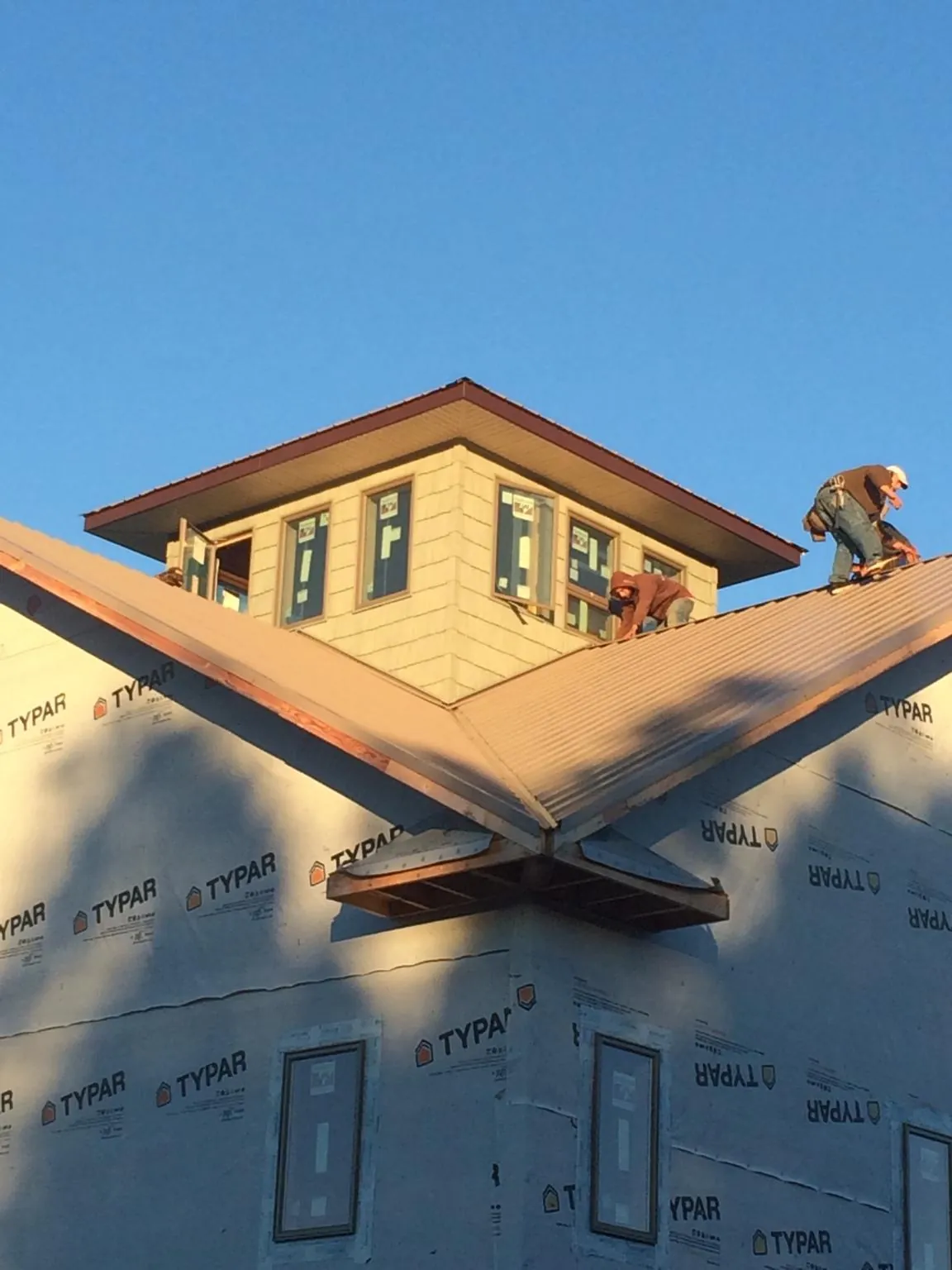 Roofers working around a rooftop cupola on a new metal roof at sunset — Roof Waterproofing in Licking by Roofing Brothers